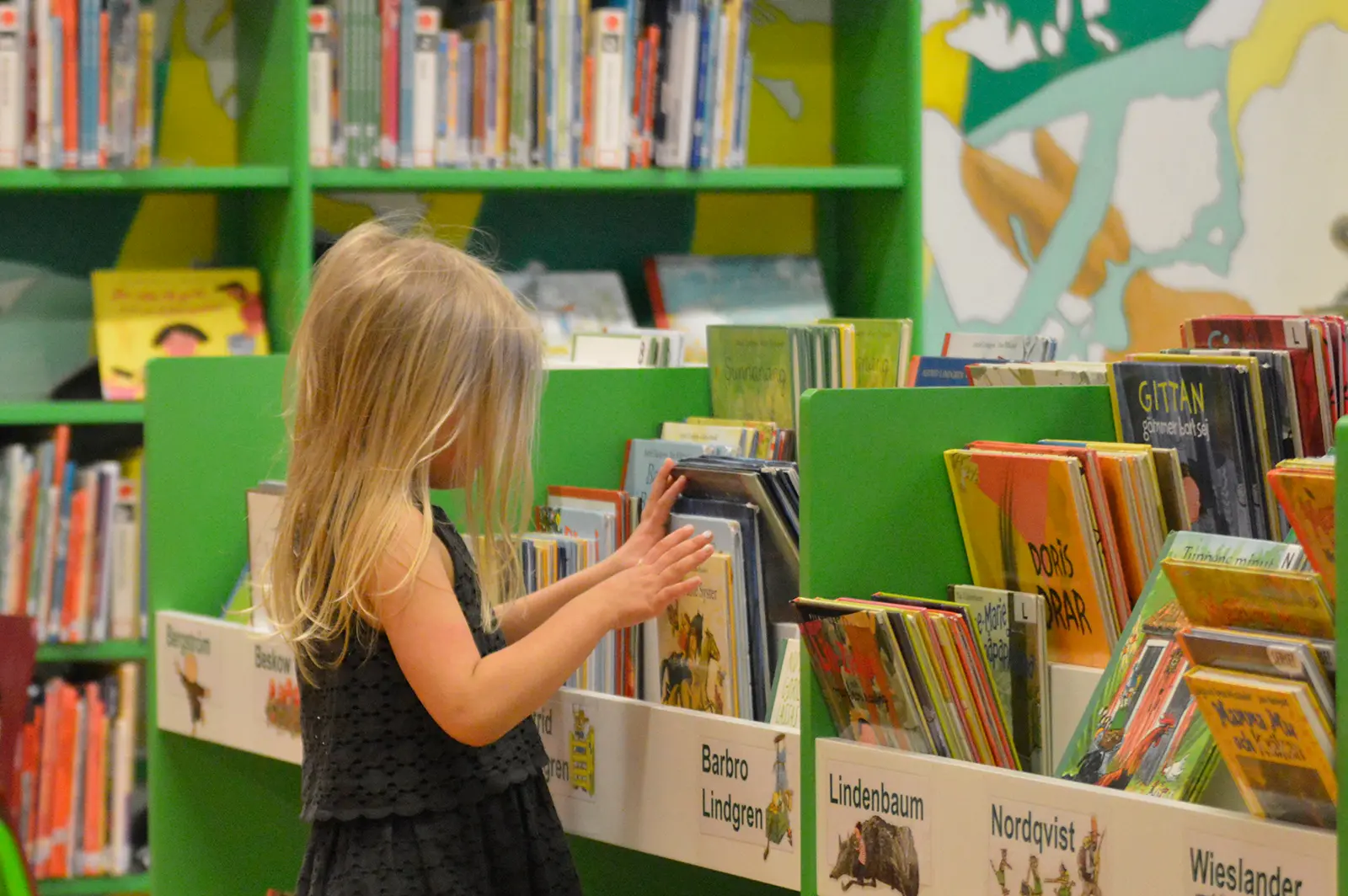 bild som visar liten flicka som bläddrar bland böcker i ett bibliotek