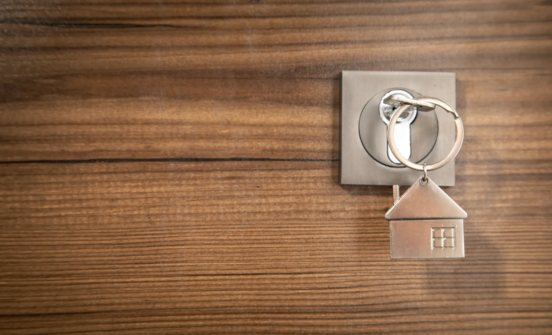 Nyckel i en dörr med en nyckelring i form av ett hus i metall