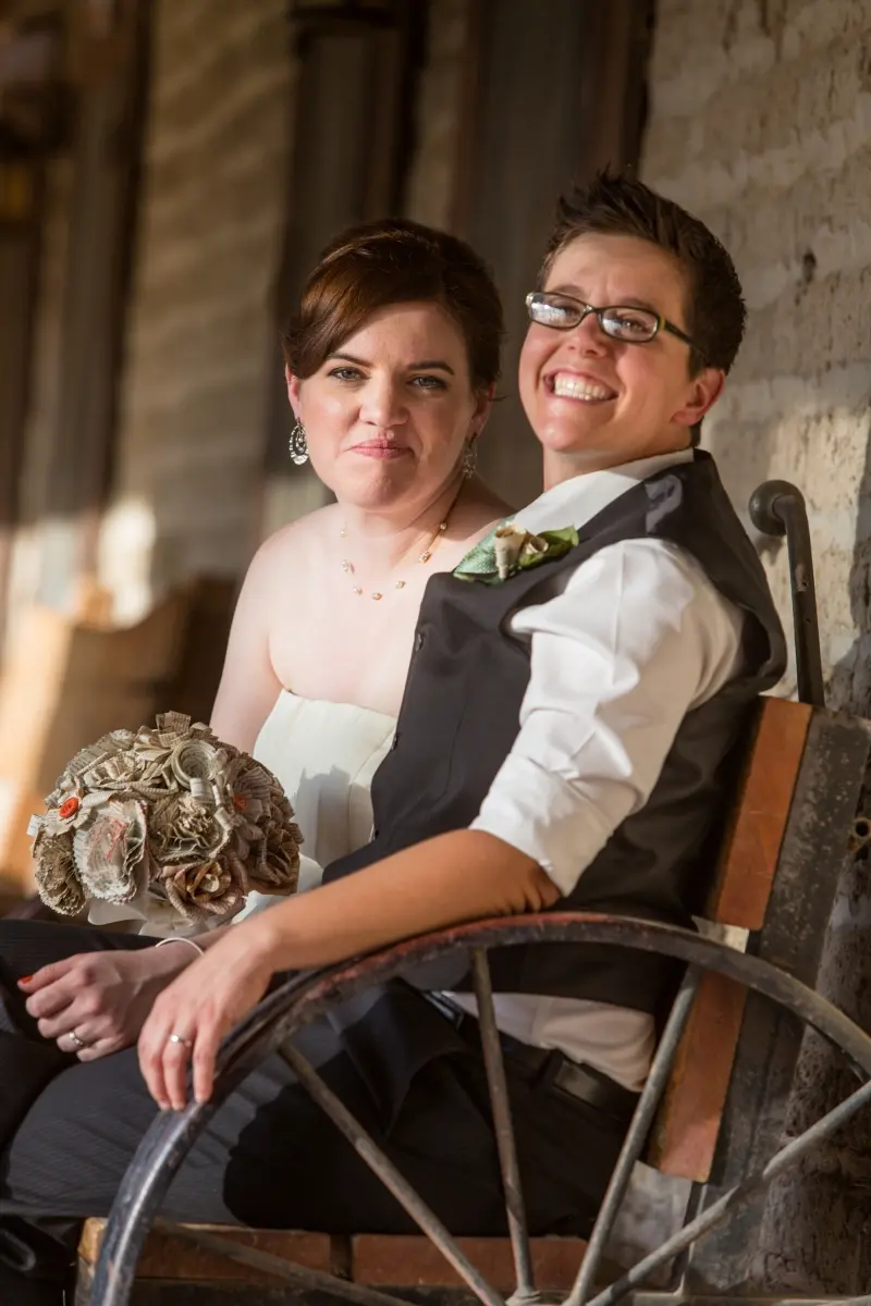 Två kvinnor iklädda festkläder, den ena håller i en brudbukett