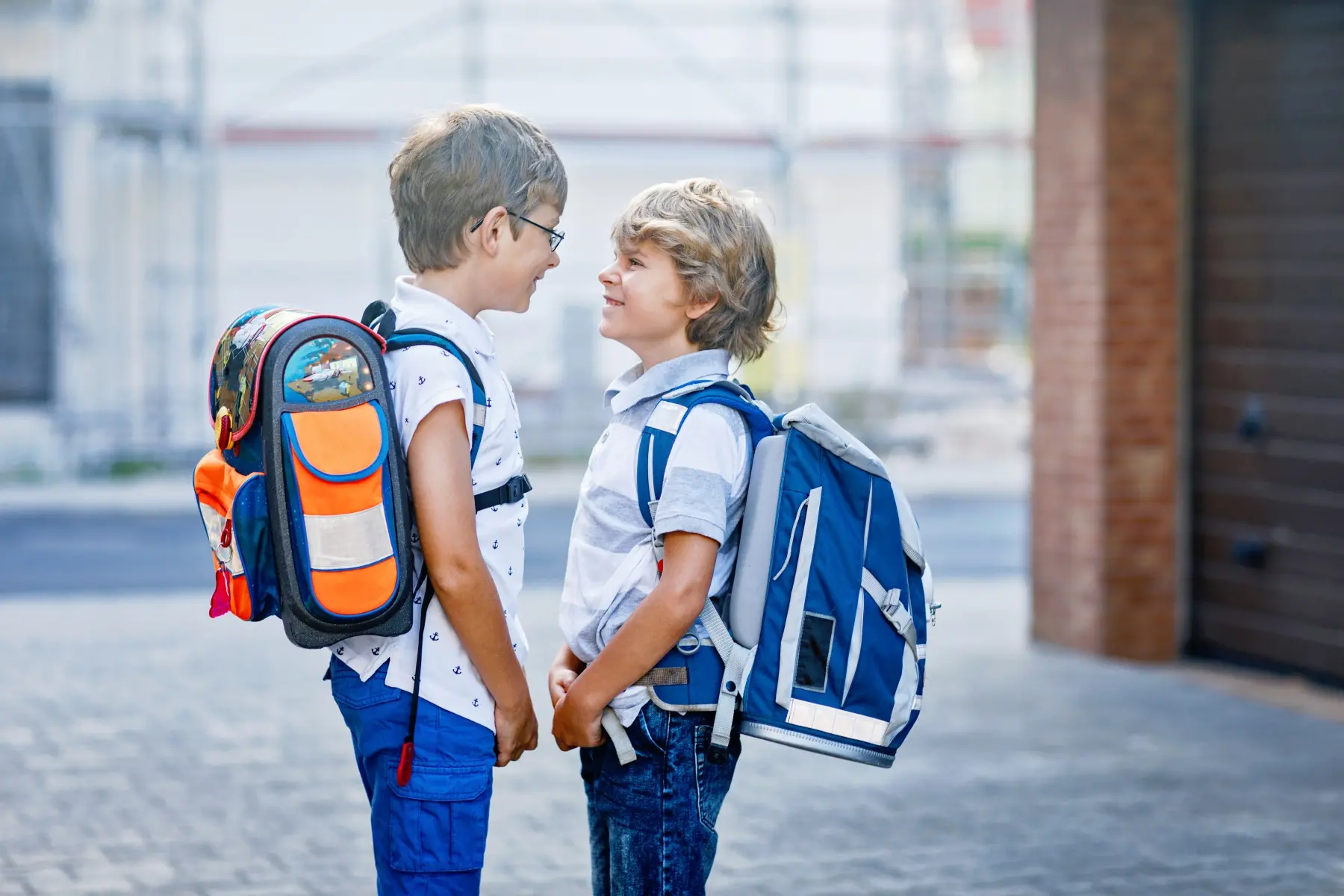 Två unga pojkar med varsin ryggsäck vända mot varandra 