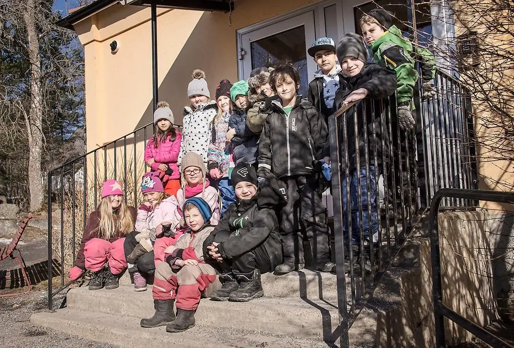 Grupp med barn framför en skolbyggnad 