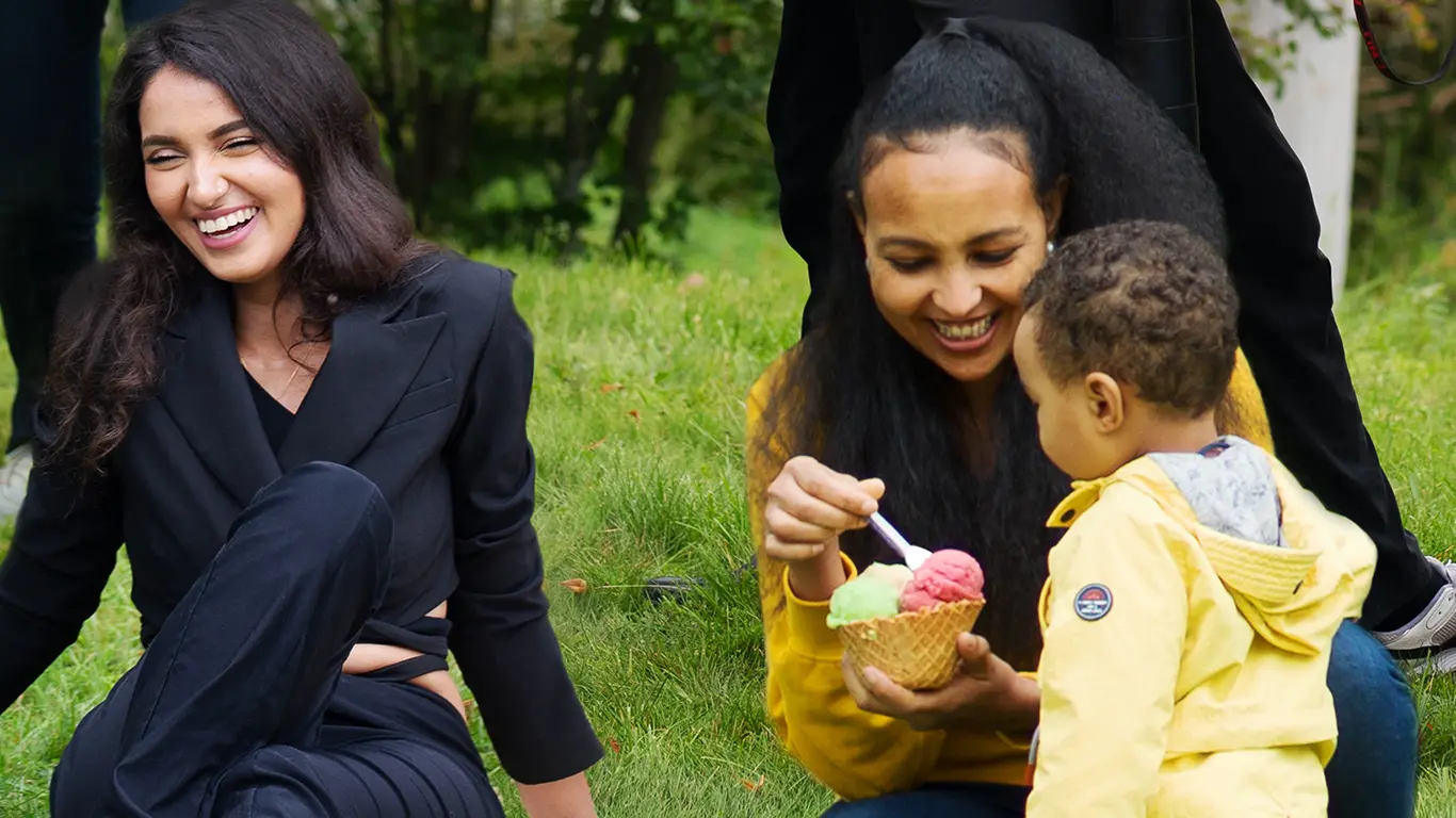 två vuxna och ett barn ute i naturen och barnet äter glass