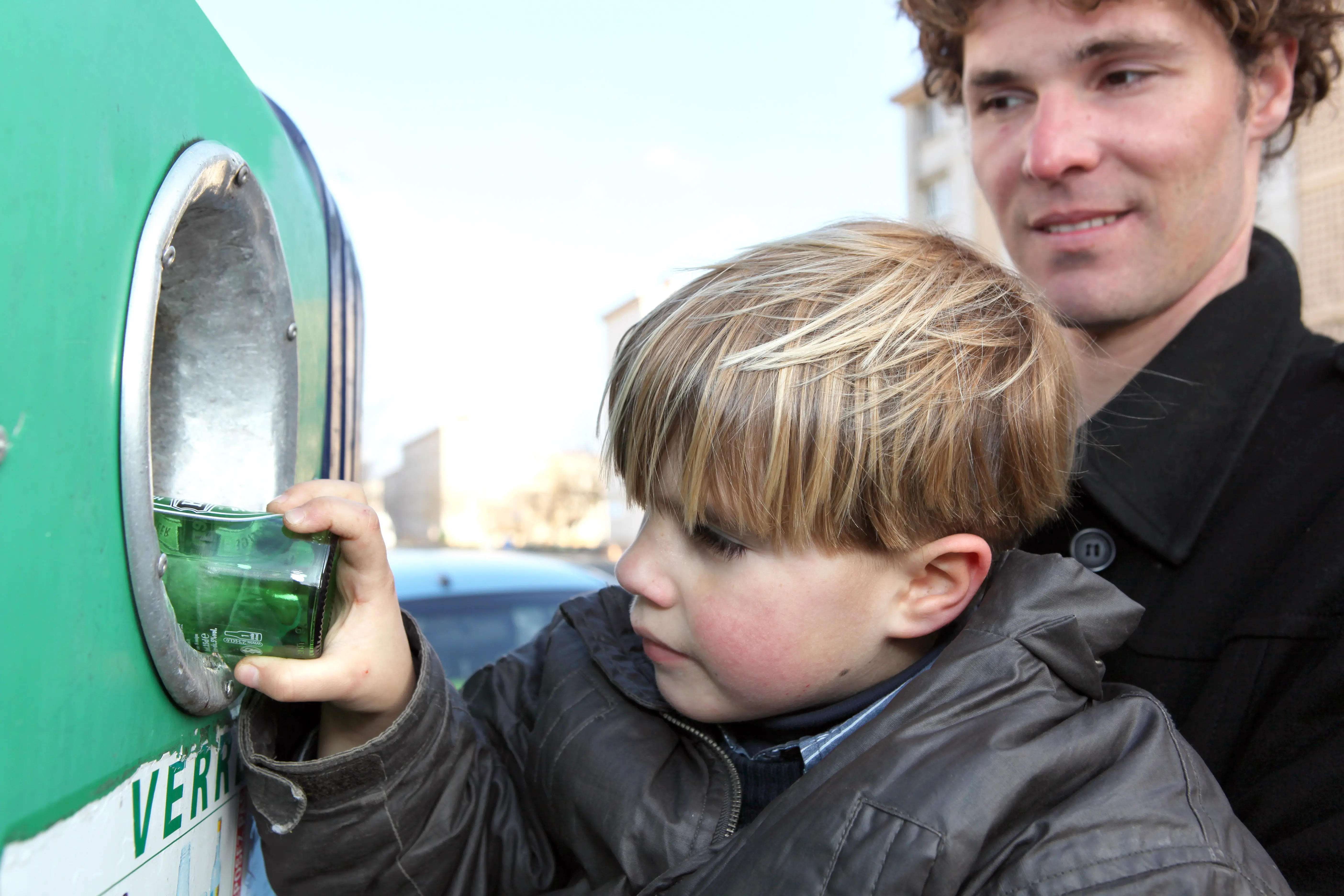 Pojke stoppar glas i återvinningskärl
