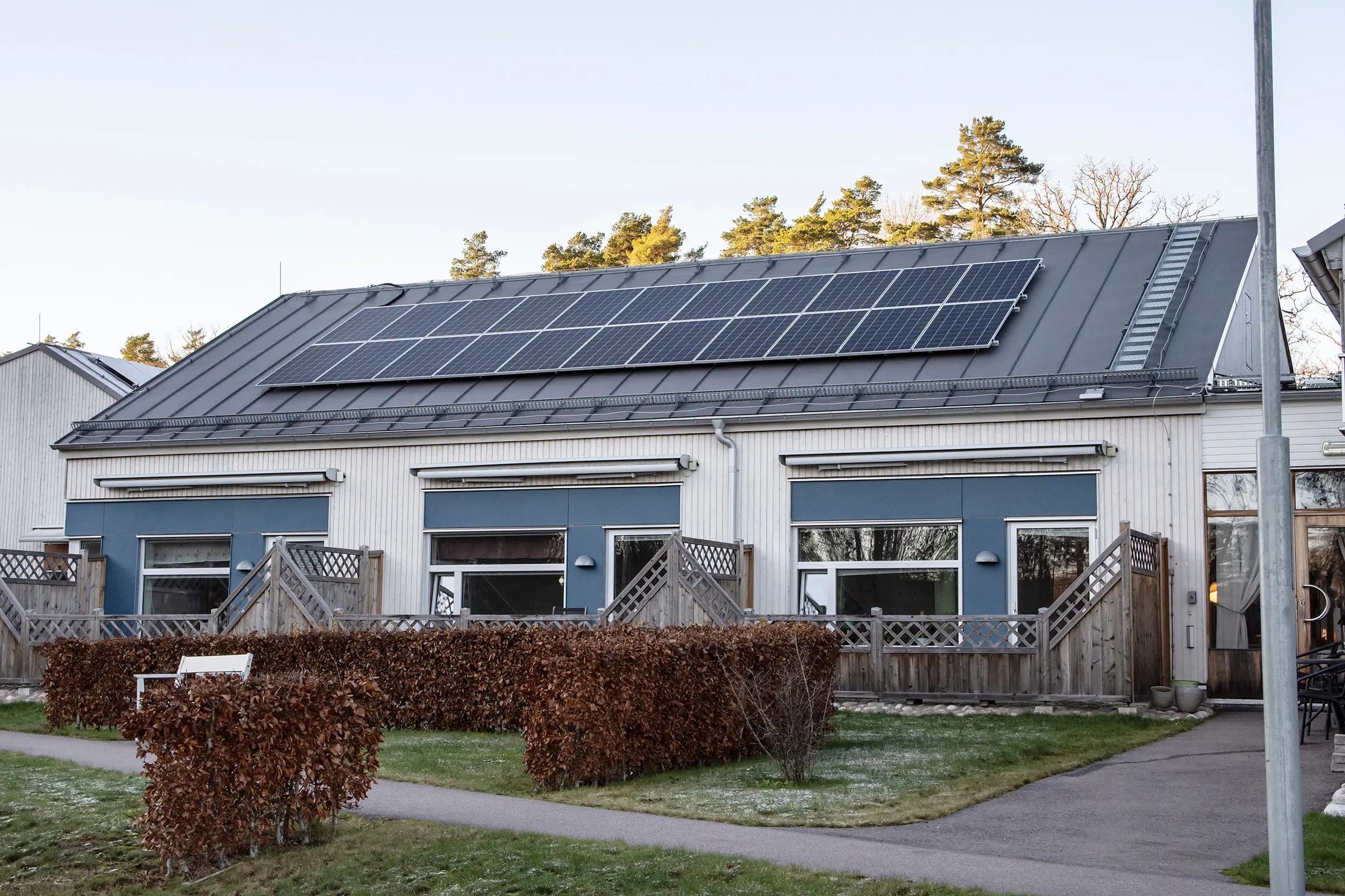 Bild på ljus byggnad med solpaneler på taket 