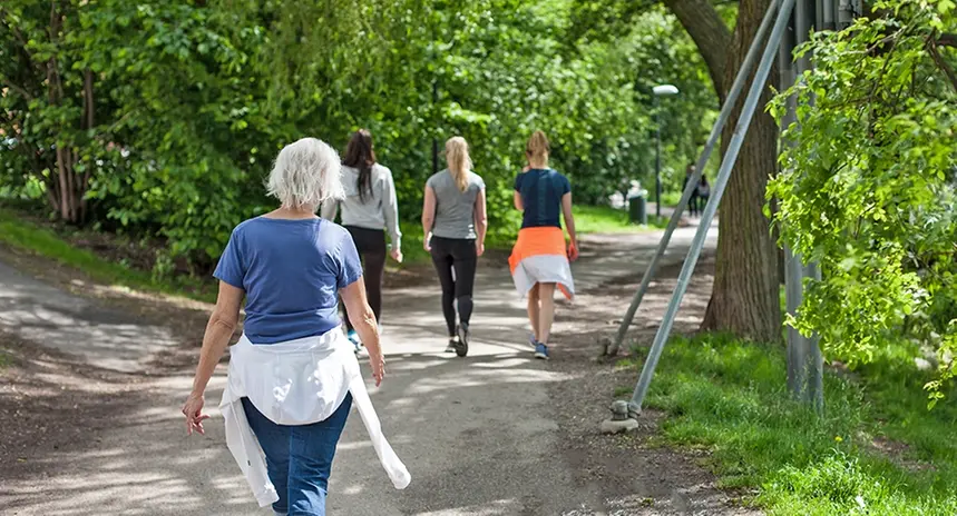 en äldre kvinna går bakom tre yngre kvinnor ute i naturen